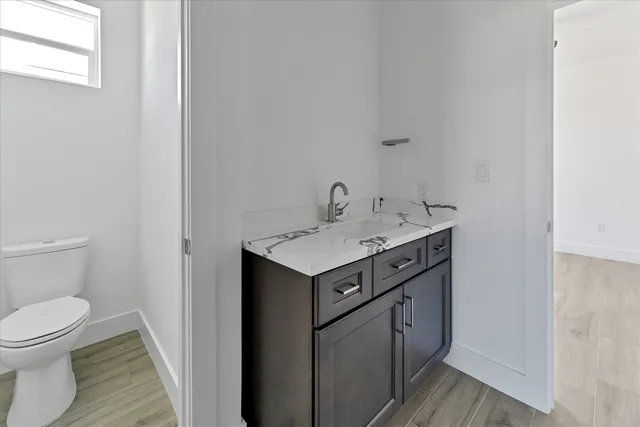 a utility room with sink toilet and wooden floor
