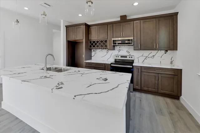 a kitchen with kitchen island granite countertop a sink stainless steel appliances and cabinets