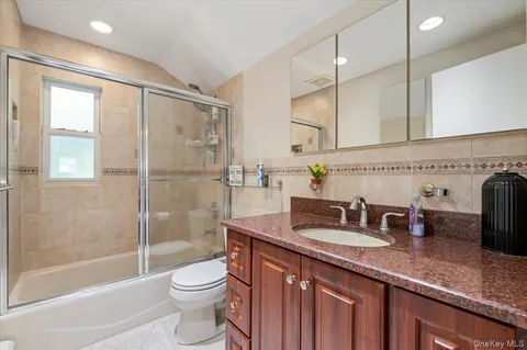a bathroom with a granite countertop sink a toilet a mirror and shower