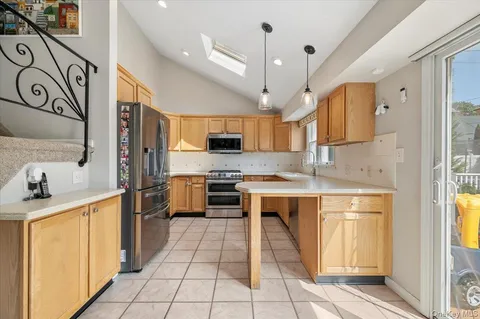 a kitchen with stainless steel appliances a sink a stove a refrigerator cabinets and a window