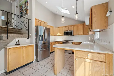 a kitchen with stainless steel appliances granite countertop a sink a stove a refrigerator a microwave oven with white cabinets