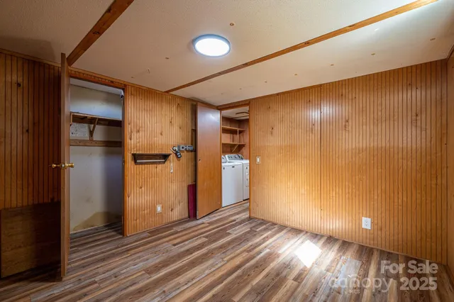 a view of an empty room with wooden floor and a bathroom