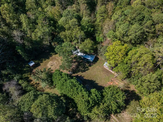 an aerial view of residential house with outdoor space and trees all around