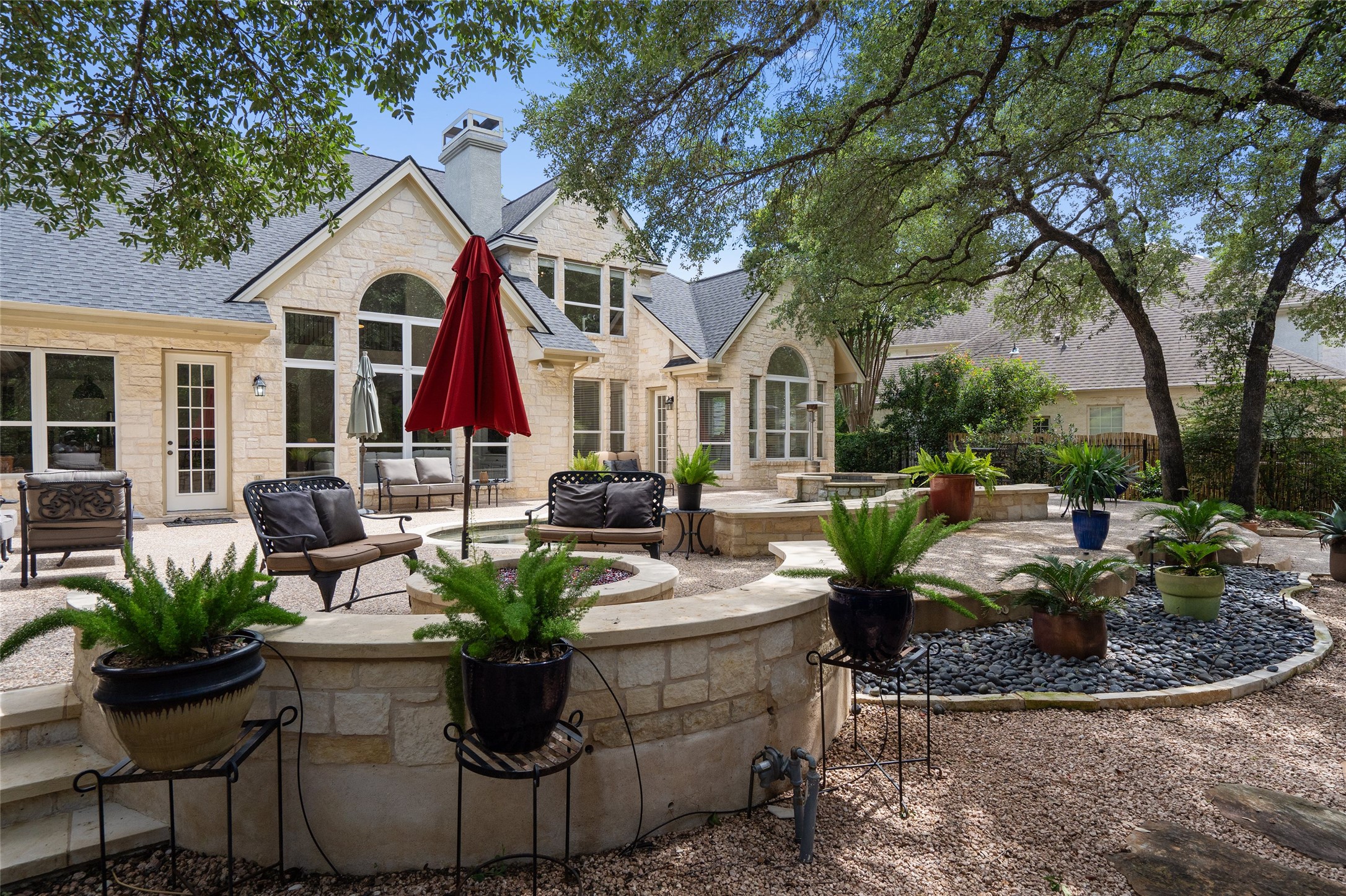 4313 Rio Robles Drive Austin, TX 78746 - Photo 36 of 40 A spacious stone patio and fire pit provide an inviting outdoor entertaining area, surrounded by mature trees.