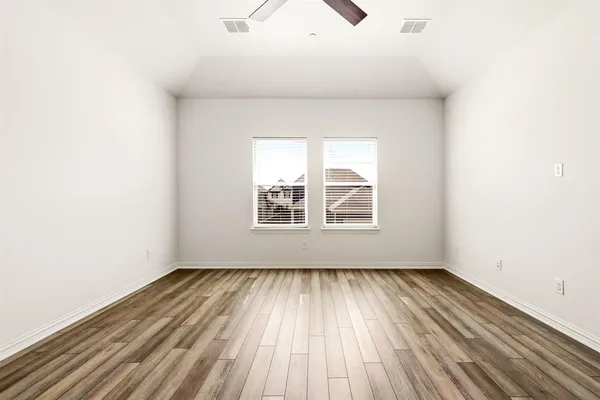 an empty room with wooden floor and windows