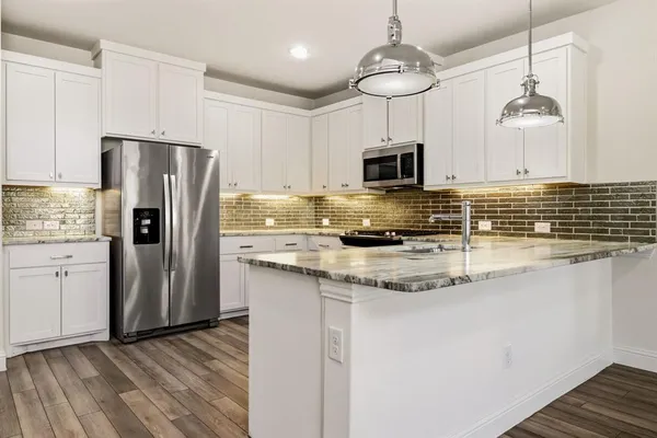 a kitchen with stainless steel appliances granite countertop a refrigerator a stove a sink and a microwave