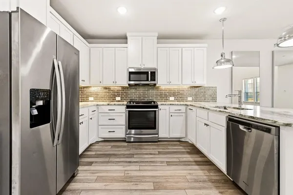 a kitchen with white cabinets and stainless steel appliances