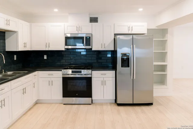 a kitchen with stainless steel appliances kitchen island granite countertop a refrigerator and a sink
