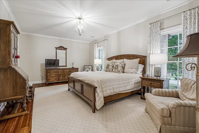 a spacious bedroom with a bed flat screen tv and a large window