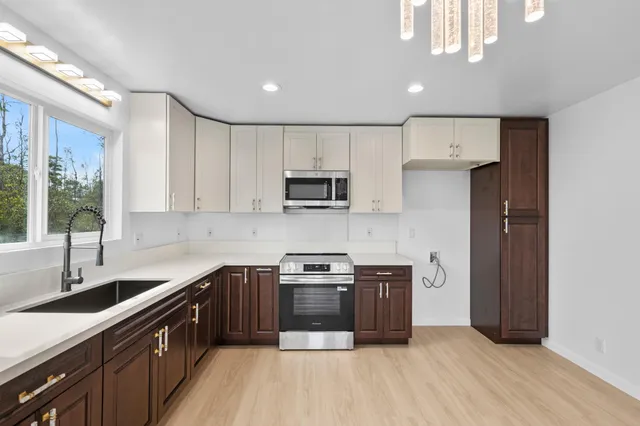 a kitchen with stainless steel appliances a sink a stove a refrigerator cabinets and a window