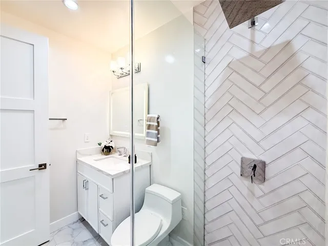 a bathroom with a toilet a sink a mirror a shower a vanity and window