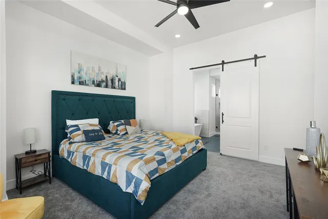 a bedroom with a bed a dresser and a chandelier