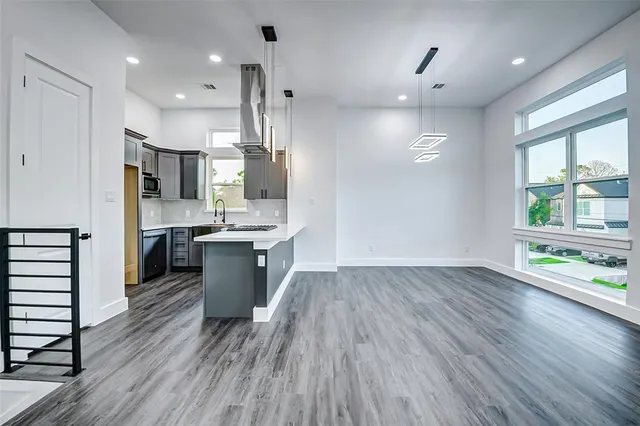 a large kitchen with stainless steel appliances a large counter top a sink a refrigerator and a window