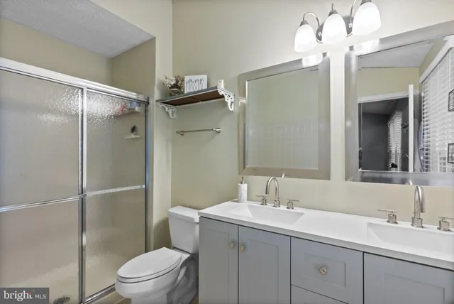 a bathroom with a shower sink vanity mirror and toilet