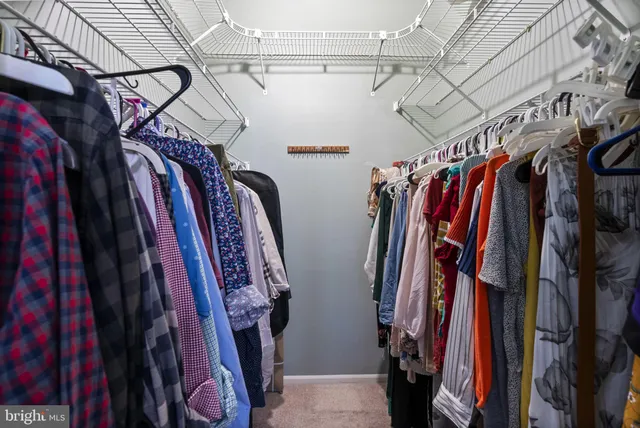 a view of walk in closet with clothes and shoes