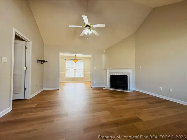 a view of an empty room with wooden floor and a fireplace