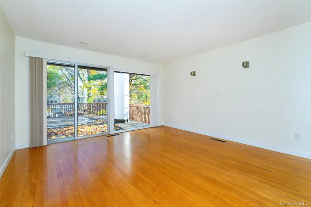 a view of empty room with wooden floor and floor to ceiling window