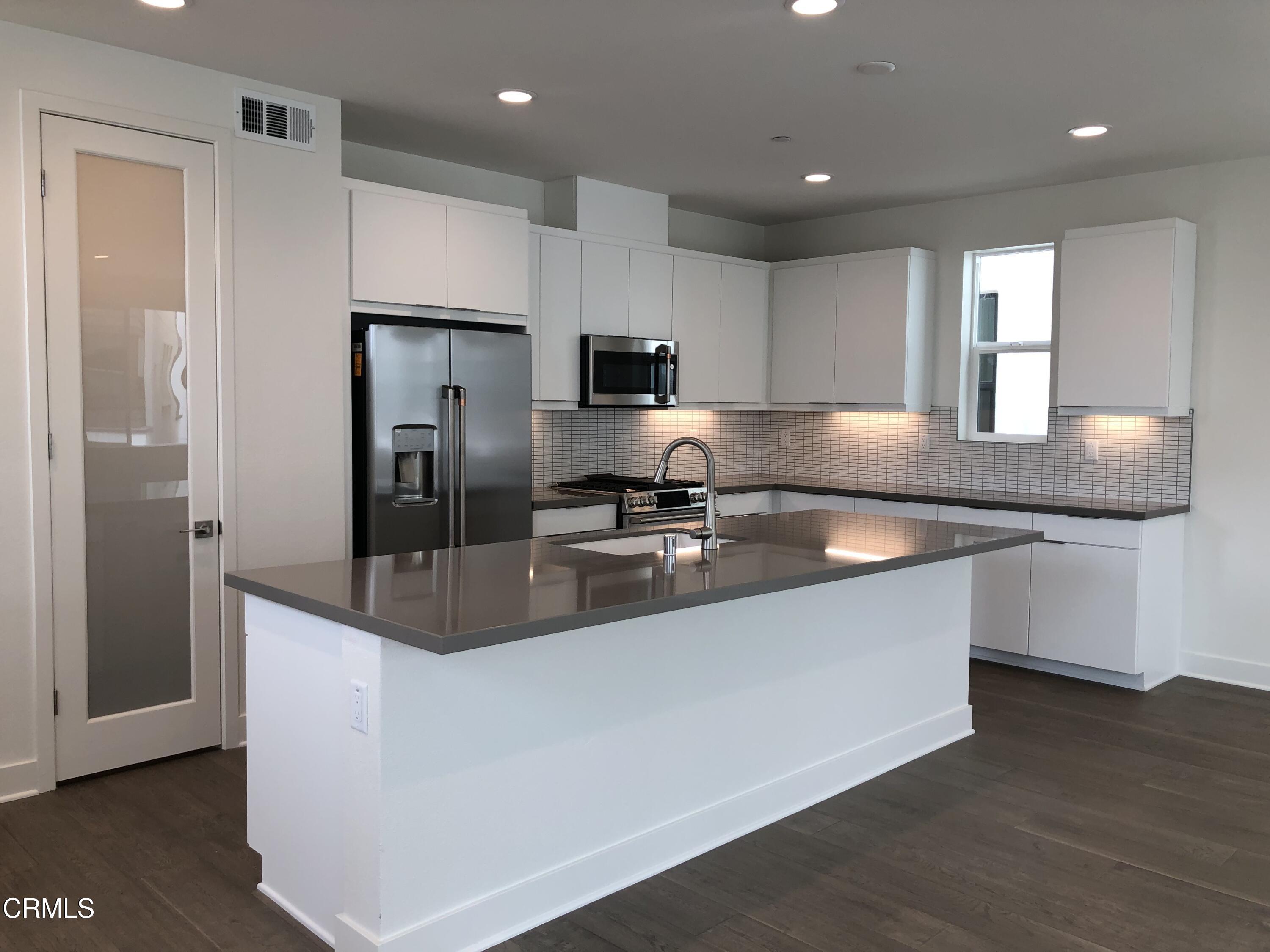 1030 Harbor Boulevard Oxnard, CA 93035 - Photo 6 of 24 a modern kitchen with stainless steel appliances granite countertop a refrigerator a sink a stove a microwave and island