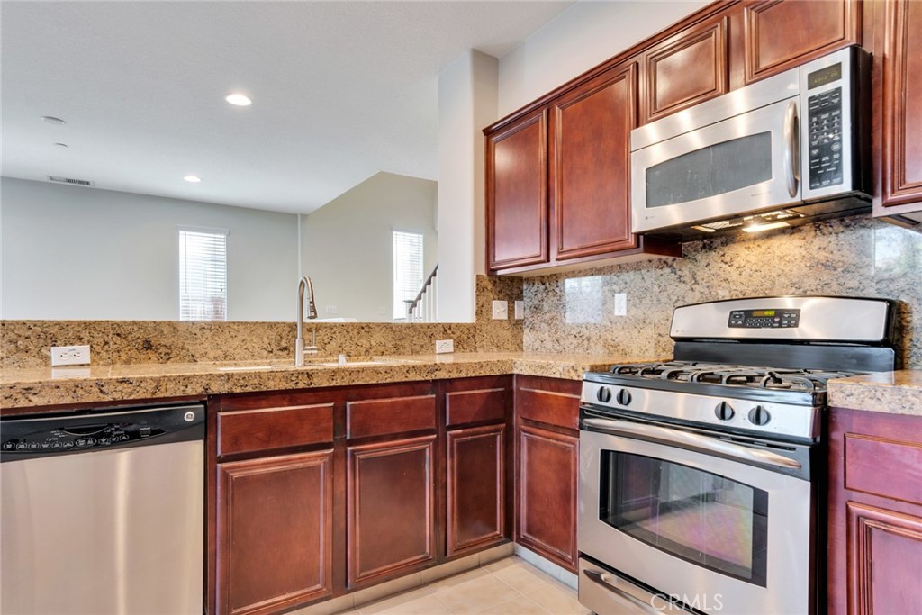 4543 Riverscape Drive Riverside, CA 92505 - Photo 12 of 25 a kitchen with stainless steel appliances granite countertop a stove top oven microwave and cabinets