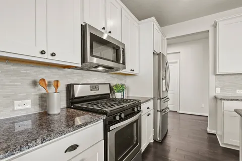 a kitchen with stainless steel appliances granite countertop a stove a microwave and a refrigerator
