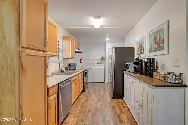 a kitchen with refrigerator a sink and wooden floor