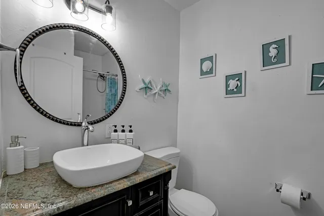 a bathroom with a granite countertop toilet a sink and mirror