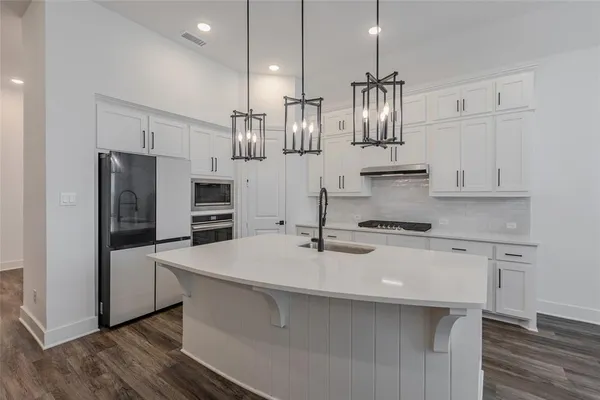 a kitchen with kitchen island white cabinets a sink dishwasher and a stove with wooden floor