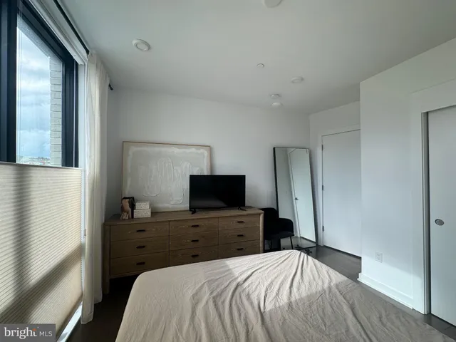 a bedroom with a bed and a flat tv screen on wall