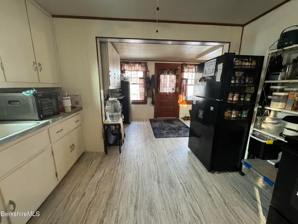 a kitchen with refrigerator and wooden floor