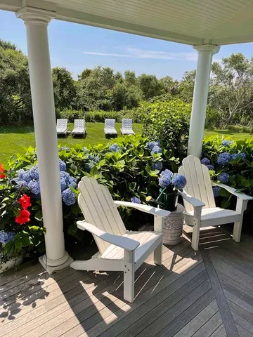 a view of a chairs and table in the patio next to a yard