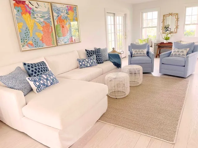a living room with couches painting on the wall and a large window