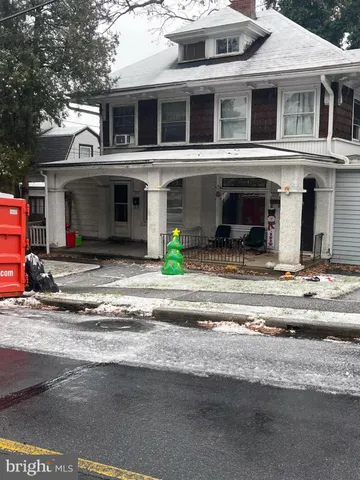 a view of a house with a barbeque and large trees