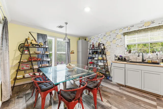 a view of a dining room and livingroom with furniture wooden floor a rug a flat screen tv a painting and a chandelier