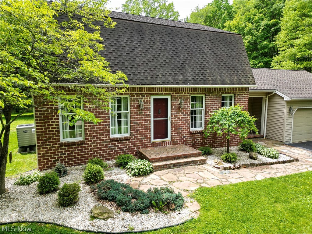 6155 Gibson Road Canfield, OH 44406 - Photo 2 of 43 Brick facade home featuring a dark red entry door, white-framed windows, and a shingle roof