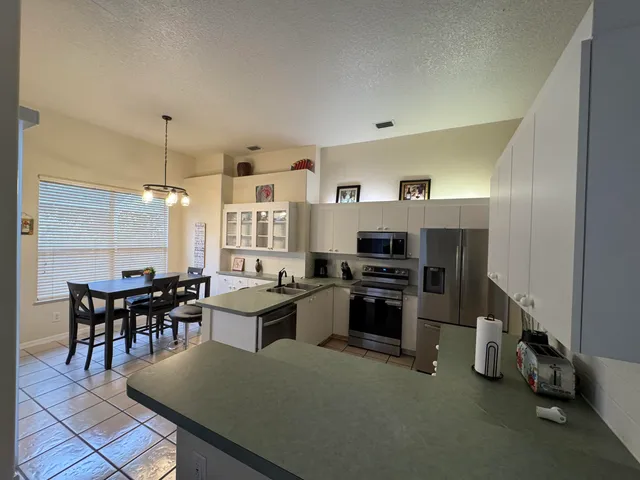 a kitchen with granite countertop a stove a sink a counter top space and cabinets