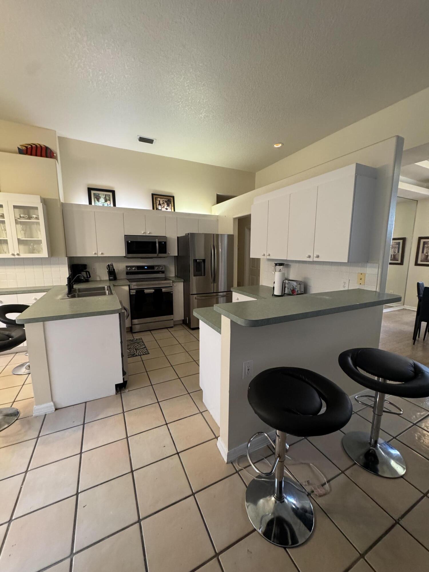 1872 Southwest Airoso Boulevard Port St. Lucie, FL 34984 - Photo 7 of 12 a kitchen with granite countertop a stove a sink a counter top space and cabinets