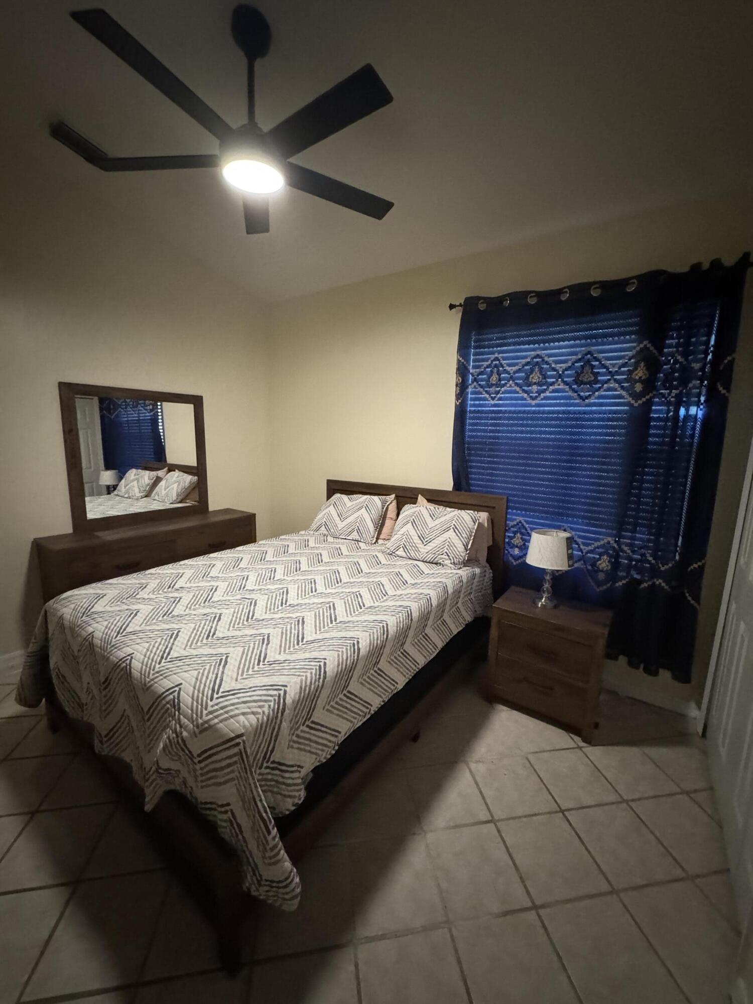 1872 Southwest Airoso Boulevard Port St. Lucie, FL 34984 - Photo 10 of 12 a bedroom with a bed and a lamp