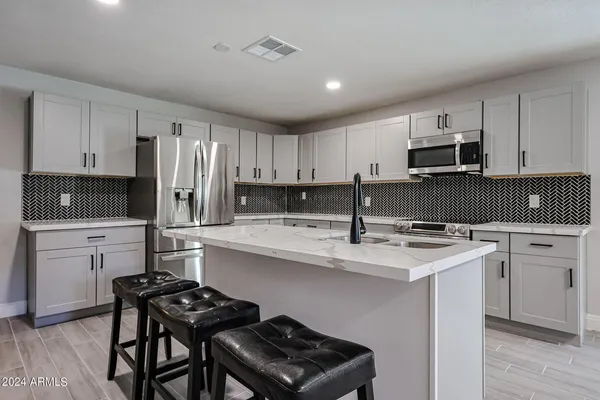 a kitchen with stainless steel appliances a stove a sink a refrigerator white cabinets and wooden floor