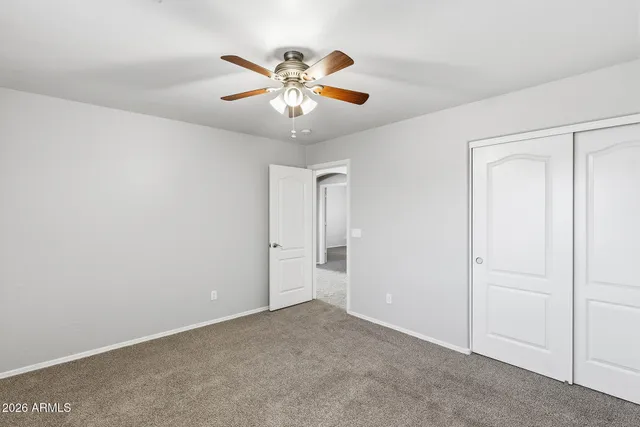 an empty room with windows and chandelier fan
