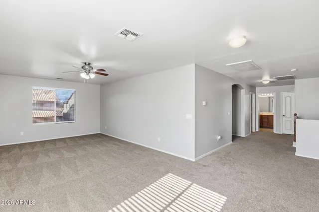 a view of an empty room with chandelier fan
