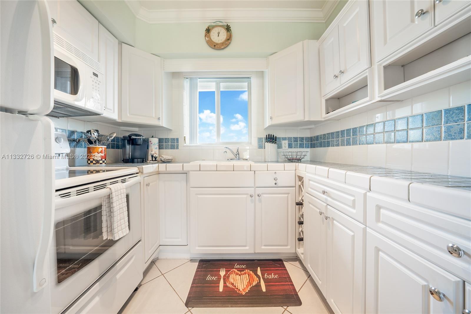 555 North Riverside Drive, Unit 15 Pompano Beach, FL 33062 - Photo 5 of 18 a kitchen with granite countertop white cabinets stainless steel appliances a sink and a window