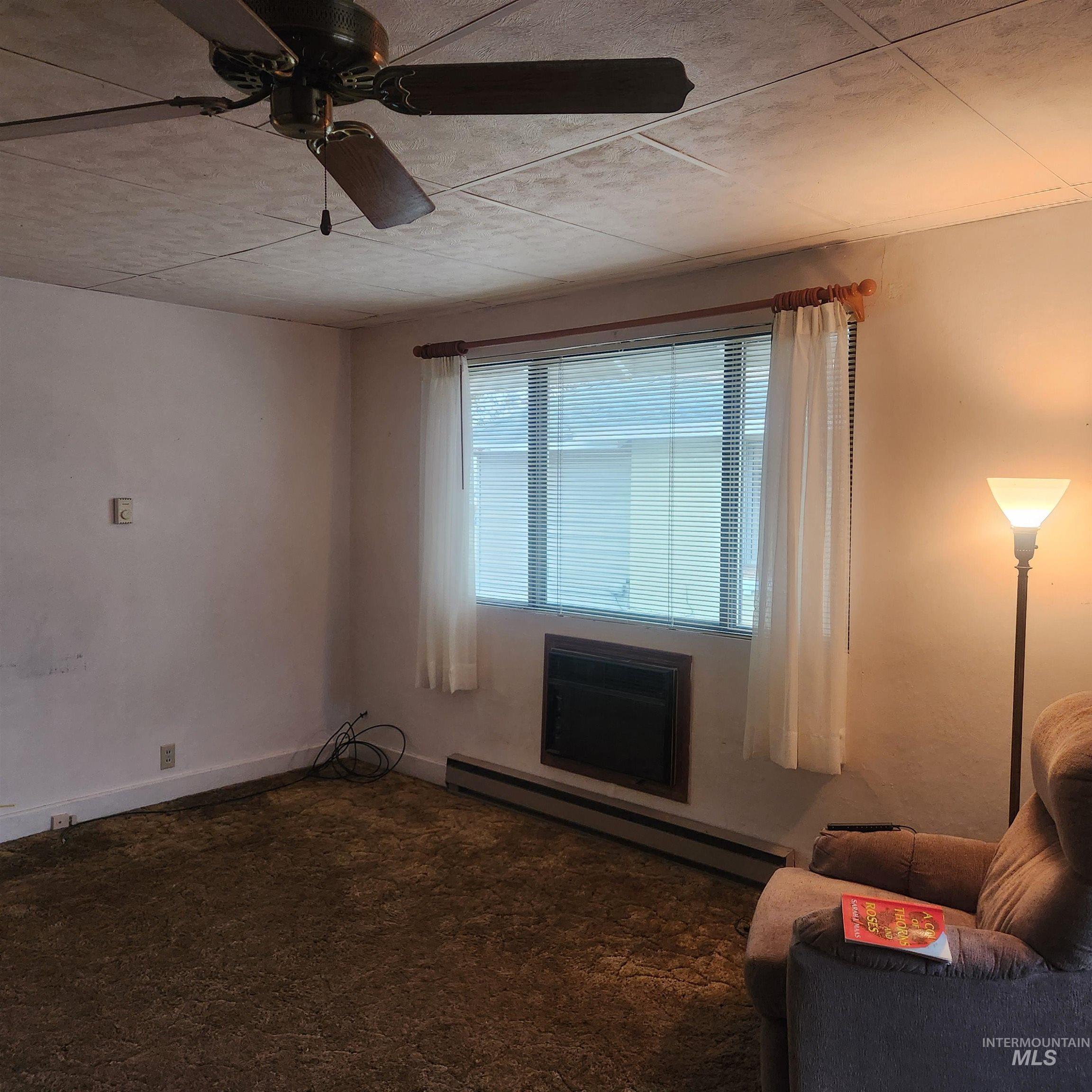 530 California Street Gooding, ID 83330 - Photo 2 of 30 Carpeted living area featuring a baseboard radiator and ceiling fan