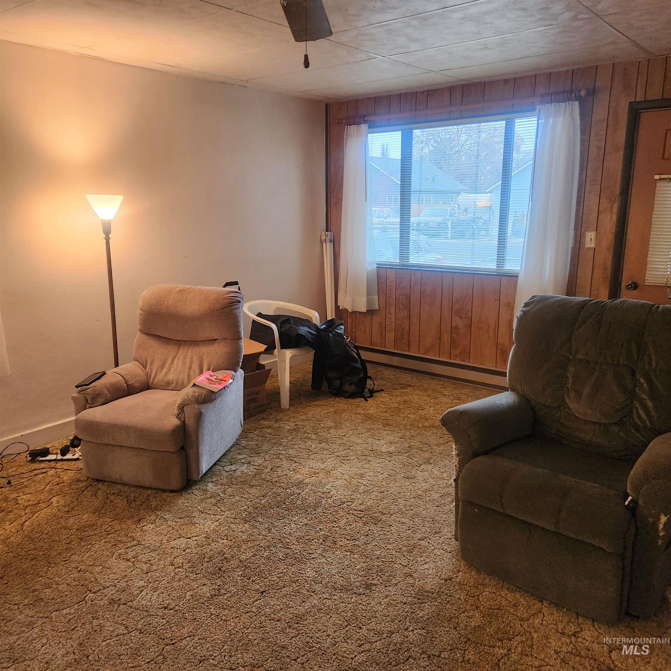530 California Street Gooding, ID 83330 - Photo 4 of 30 Sitting room featuring carpet, ceiling fan, wood walls, and a baseboard heating unit