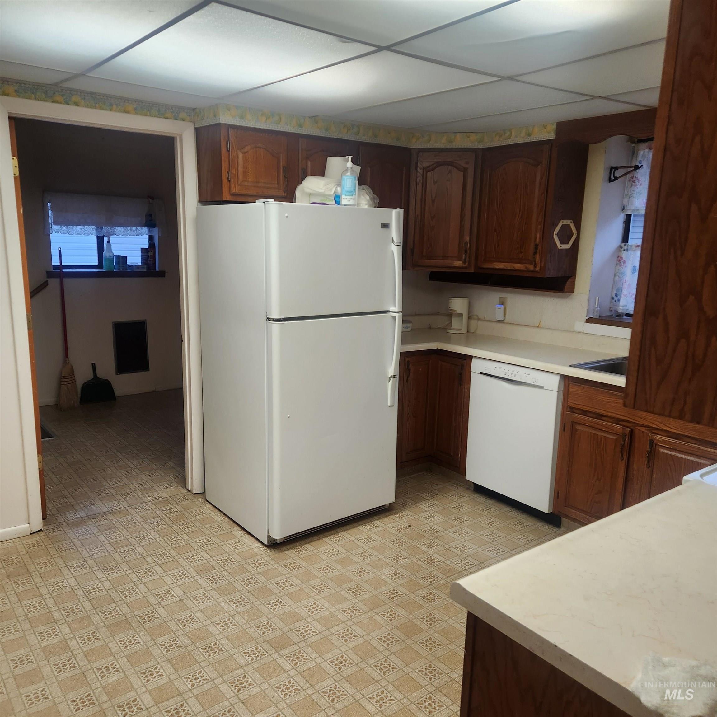 530 California Street Gooding, ID 83330 - Photo 6 of 30 Kitchen featuring light countertops, white appliances, light flooring, dark wood finish cabinetry, and a paneled ceiling