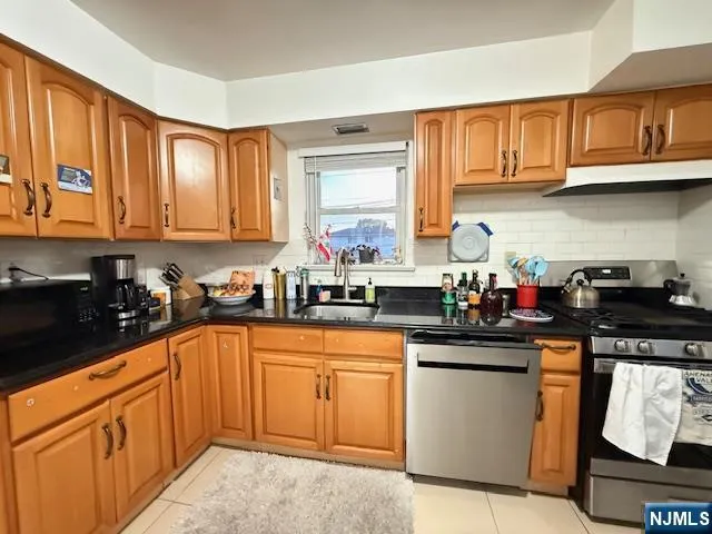 a kitchen with stainless steel appliances granite countertop a sink stove cabinets and a window