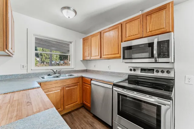 a kitchen with stainless steel appliances granite countertop wooden cabinets stove top oven and sink