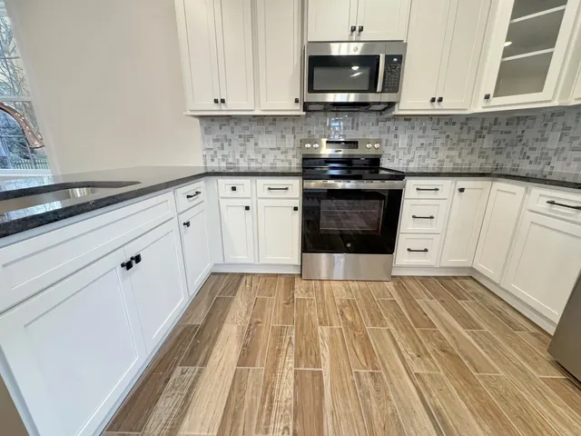 a kitchen with granite countertop white cabinets and stainless steel appliances