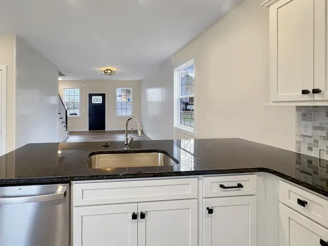 a view with granite countertop a sink and cabinets