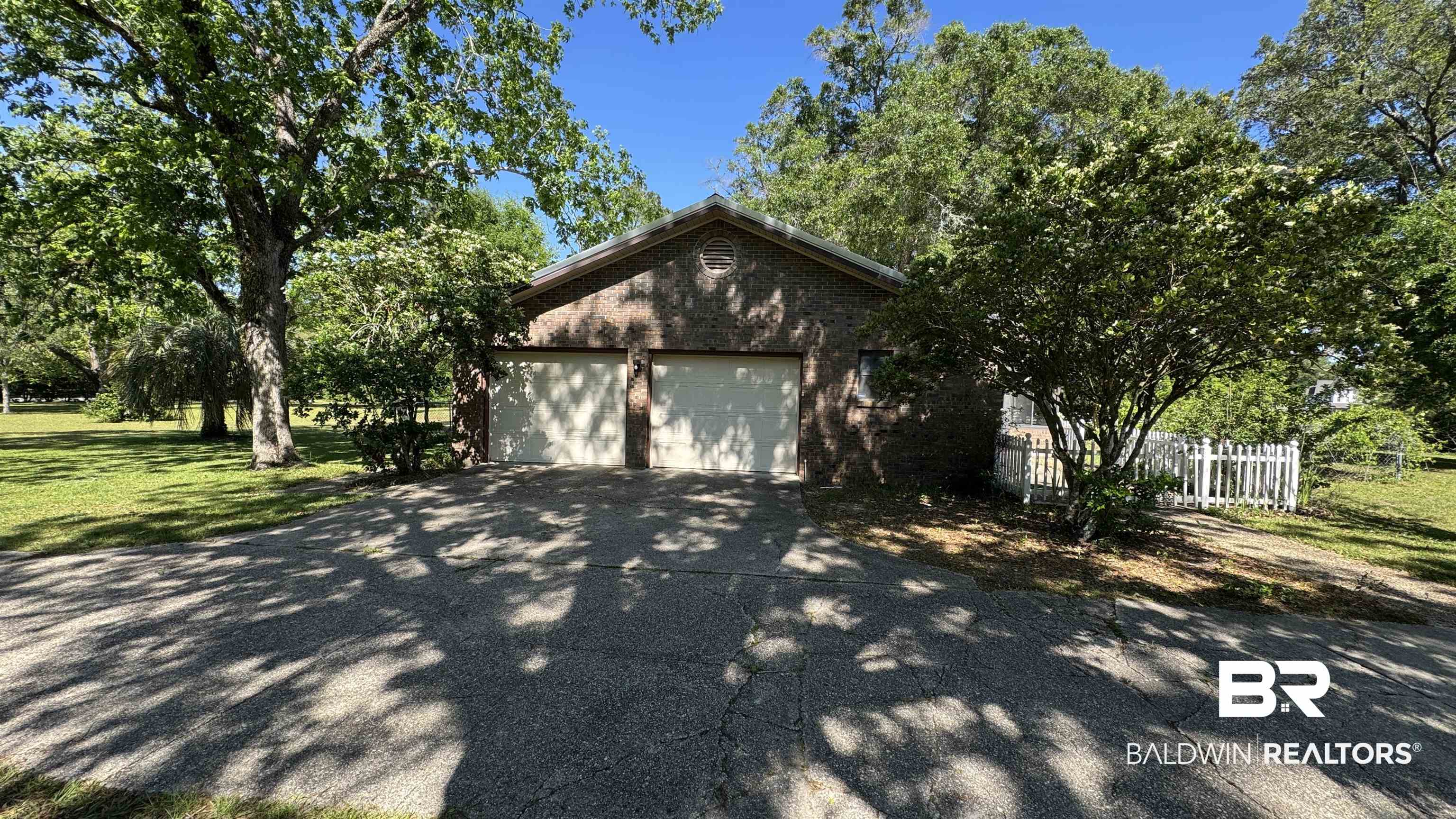 33370 Highway 98 Lillian, AL 36549 - Photo 11 of 58 Brick-clad two-car garage with white paneled doors, set on a paved driveway