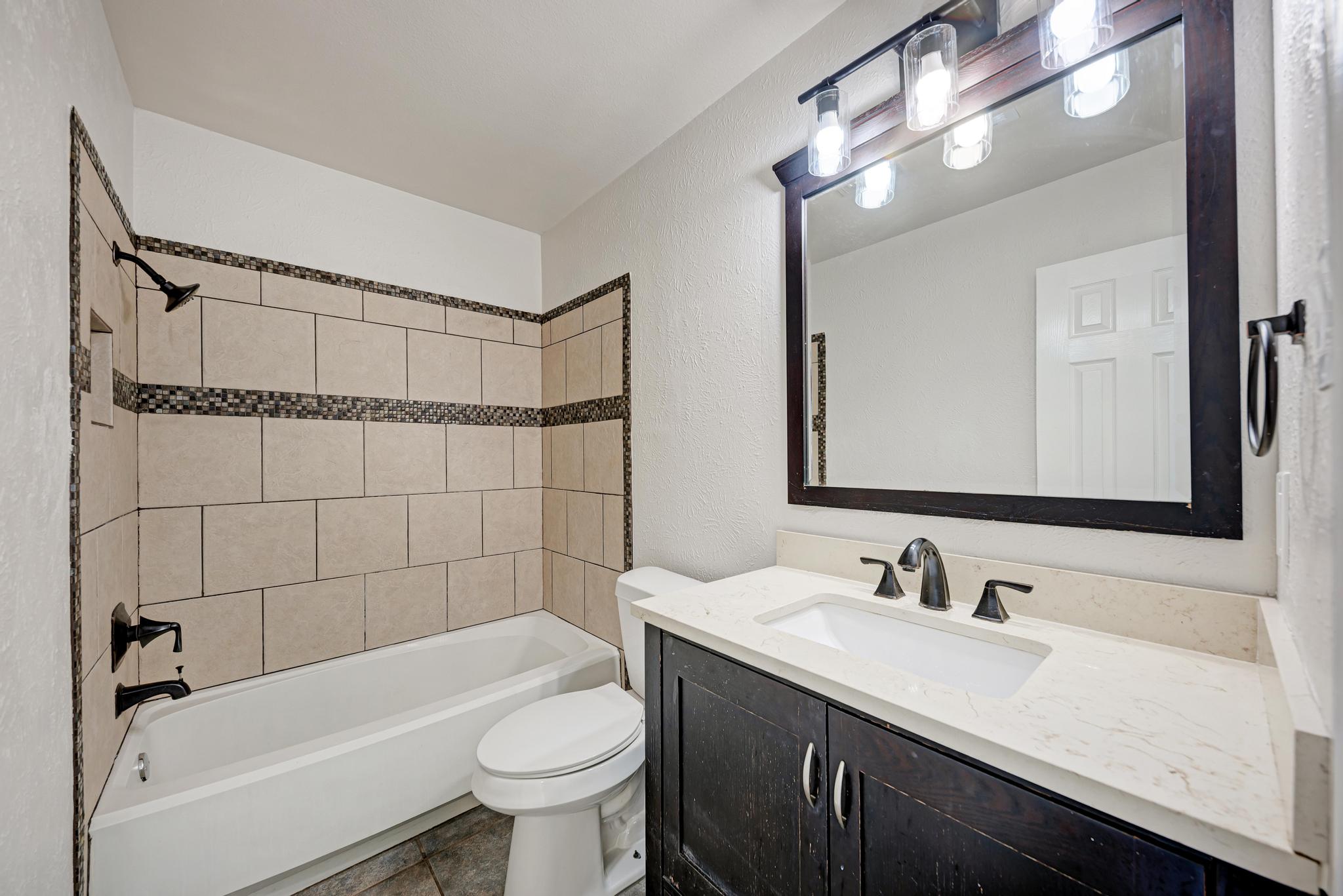 12108 Carnforth Drive Austin, TX 78753 - Photo 20 of 33 a bathroom with a sink a toilet a mirror a bathtub and shower
